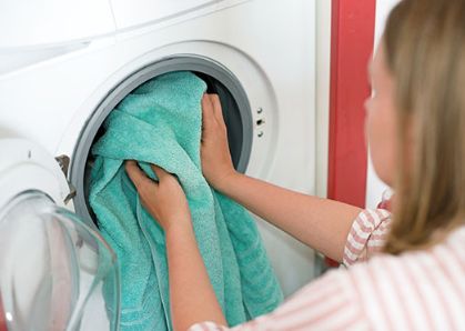 Bild: Frau tut Handtücher in die Waschmaschine