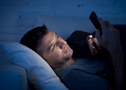 Bild: Mann im Bett am Handy