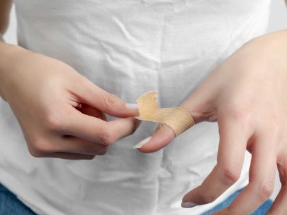 Bild: Frau bindet sich Pflaster um den Finger