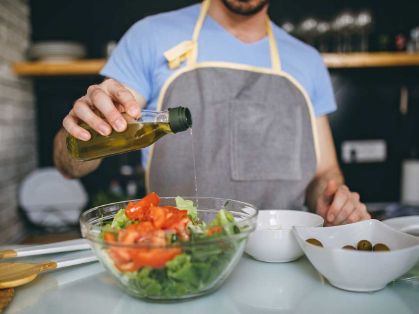 Bild: Mann gießt Öl in den Salat