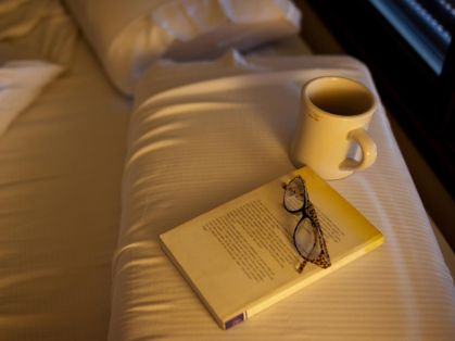 Bild: Bett mit Buch, Tasse und Brille