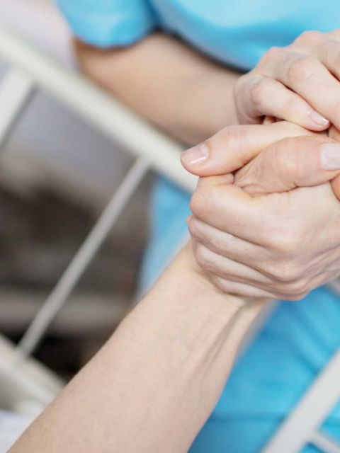 Bild: Pflegefachfrau hält Hand der Pateintin